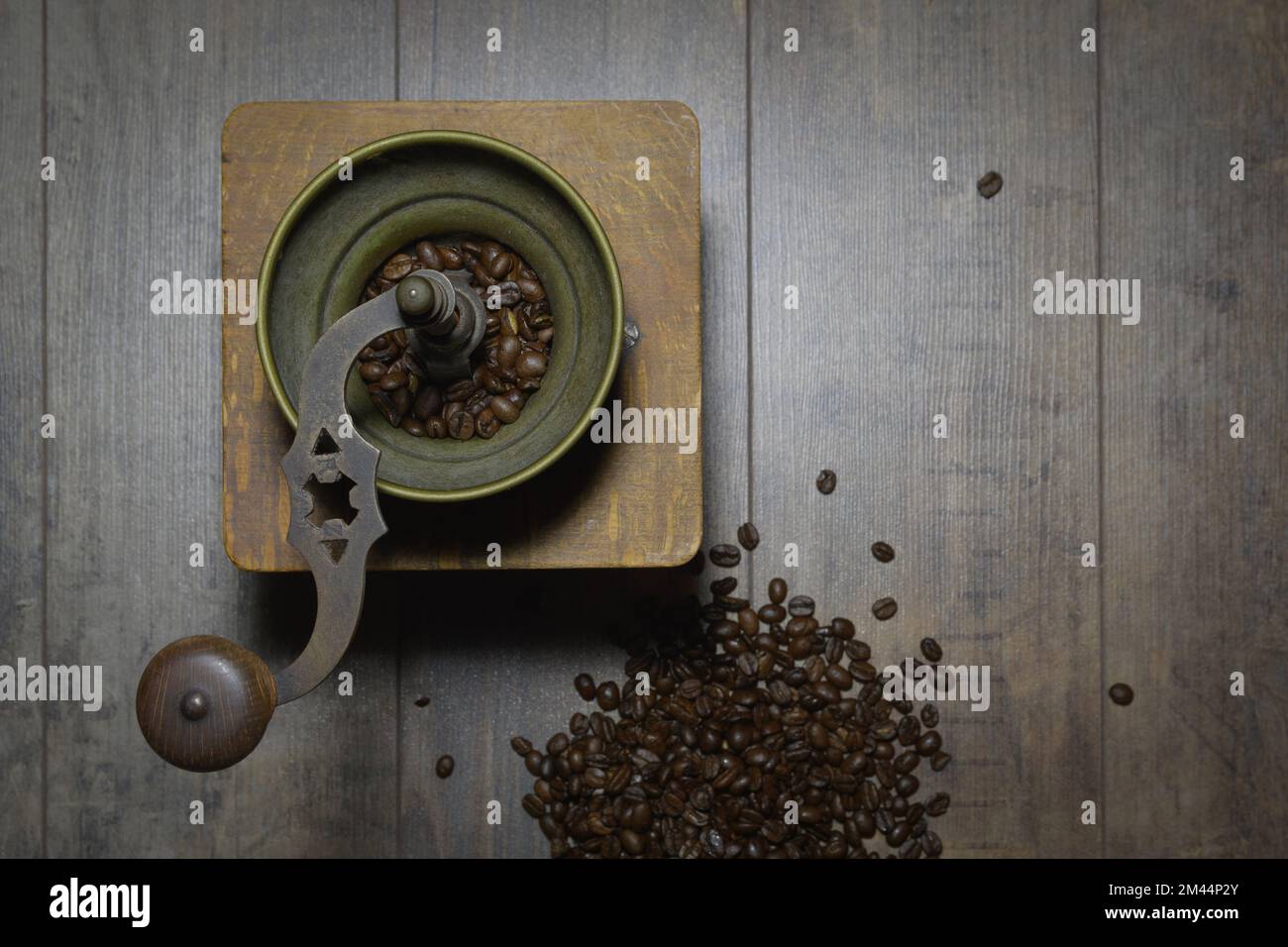 Old manual coffee grinder. Retro background with scattered coffee beans Stock Photo