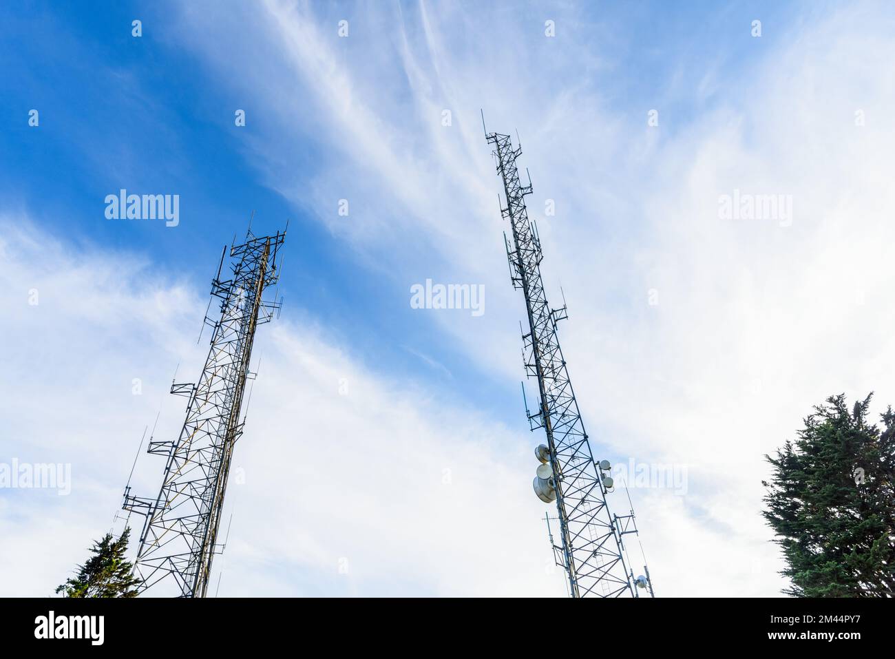 Telecommunication towers against blue sky with clouds Stock Photo - Alamy