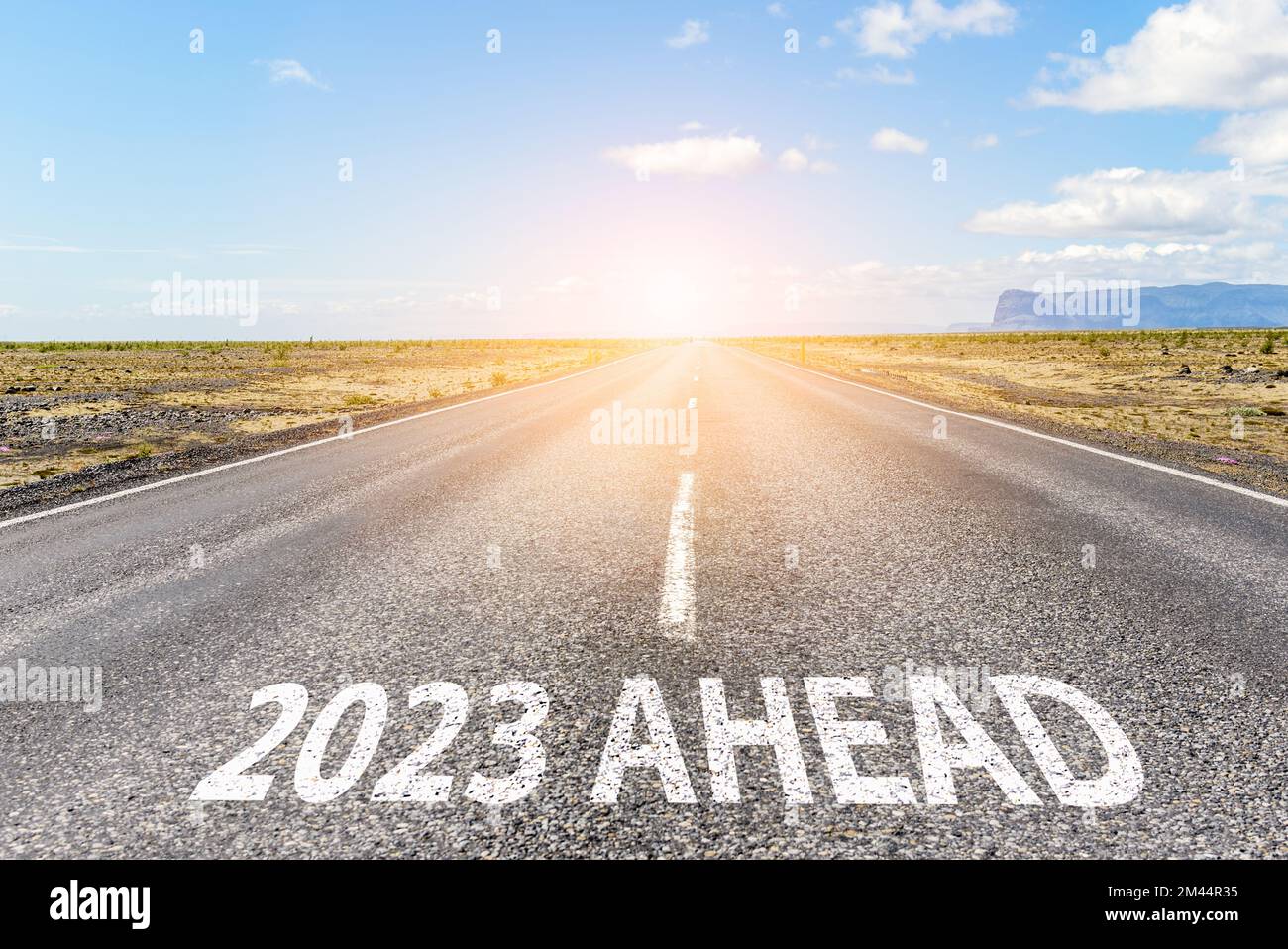 New year 2023 ahead. Conceptual empty straight road in a flat landscape with the phrase 2023 ahead painted on asphalt Stock Photo