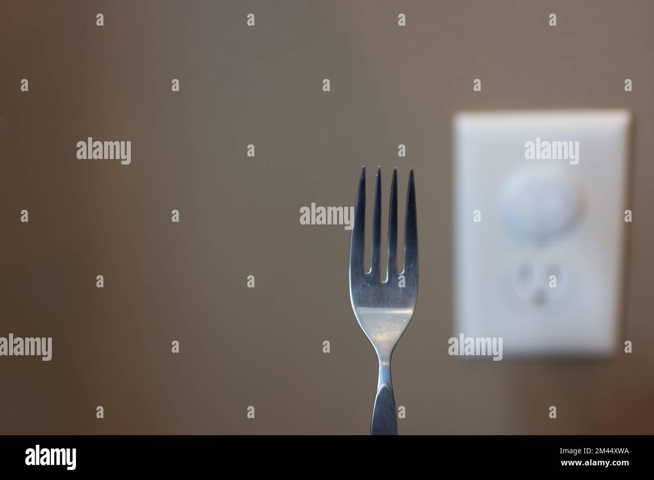 Selective focus on edge of a metal fork about to be inserted into an