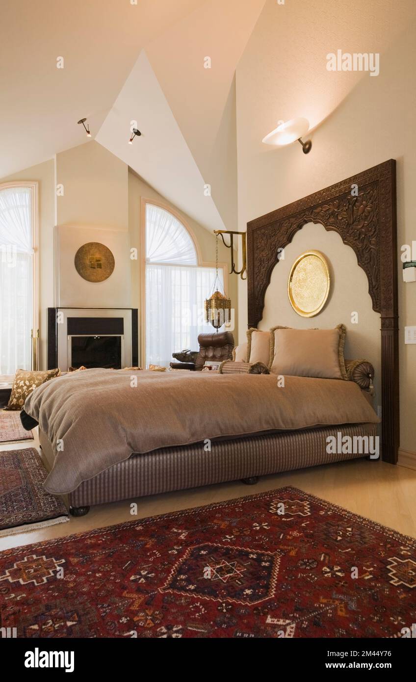 Queen size bed with wooden headboard in Moroccan style decorated master bedroom inside luxurious