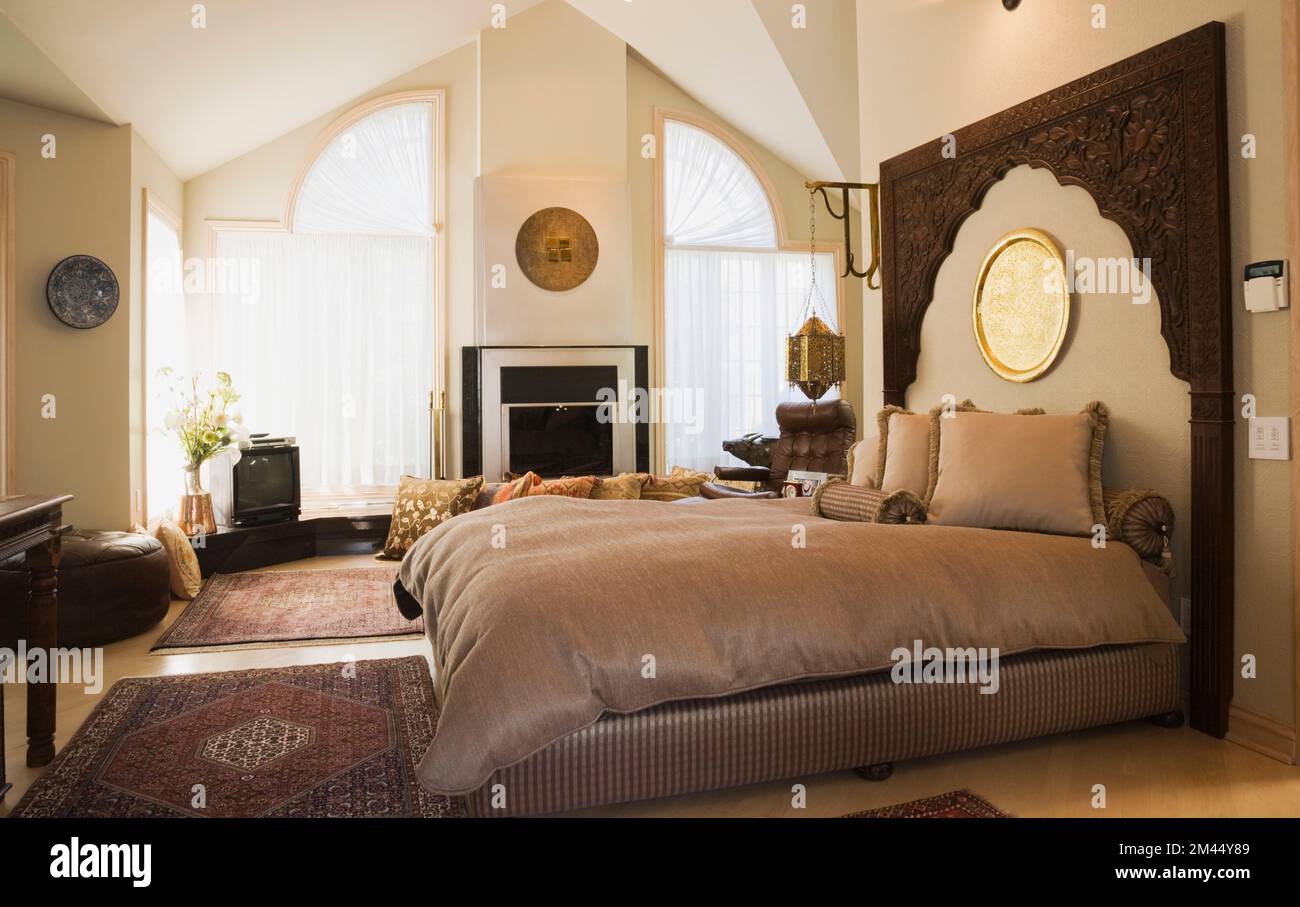 Queen size bed with wooden headboard in Moroccan style decorated master bedroom inside luxurious