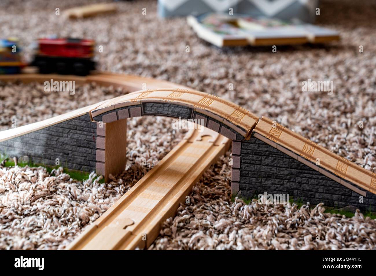 selective focus on wooden toy train track with blurred bridge and