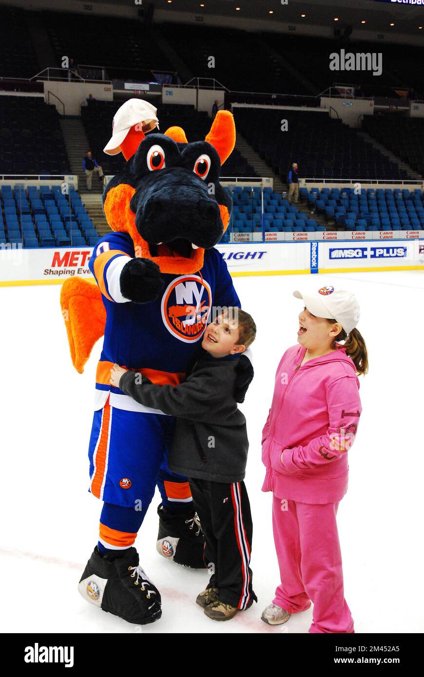 Two children greet Sparky, the dragon mascot for the NHL New York Islanders on the hockey team's ice rink Stock Photo