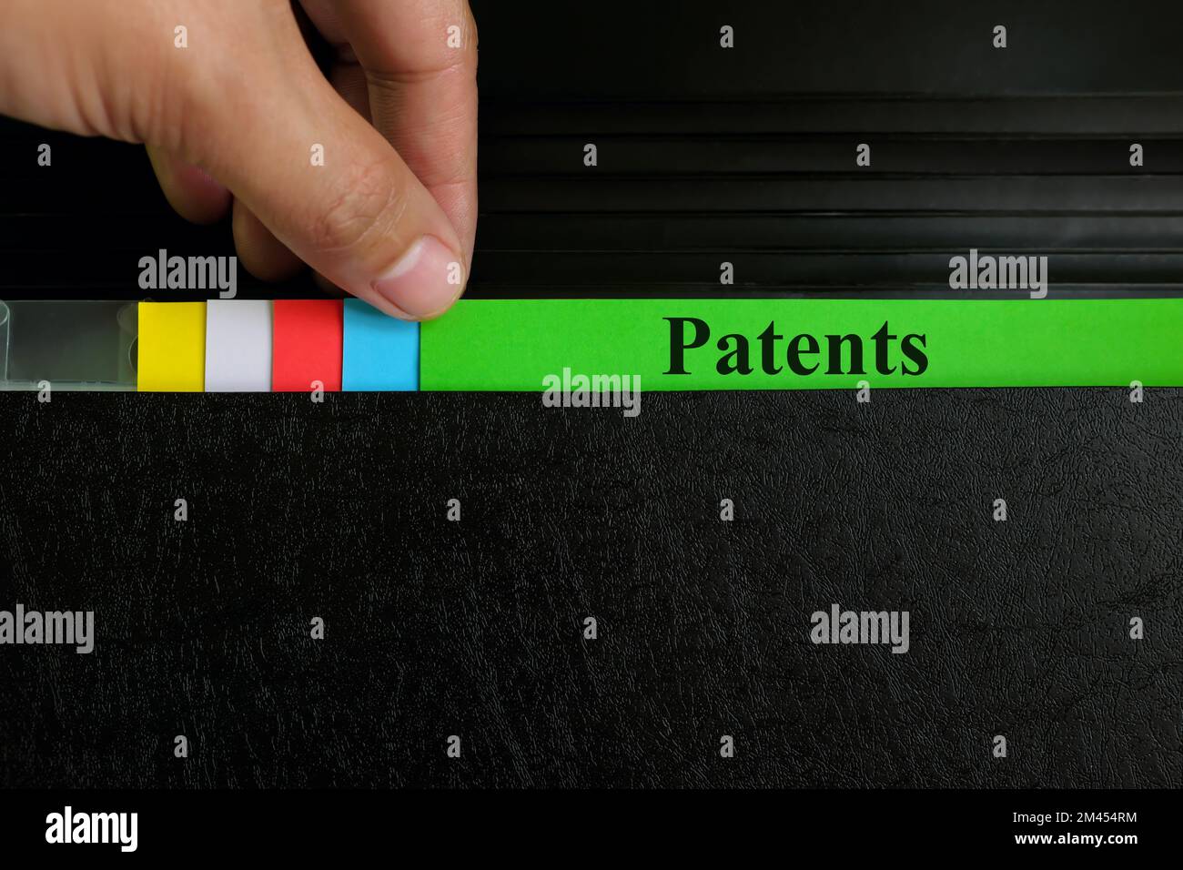 Hand picking patents file record in black binder folder. Patent and