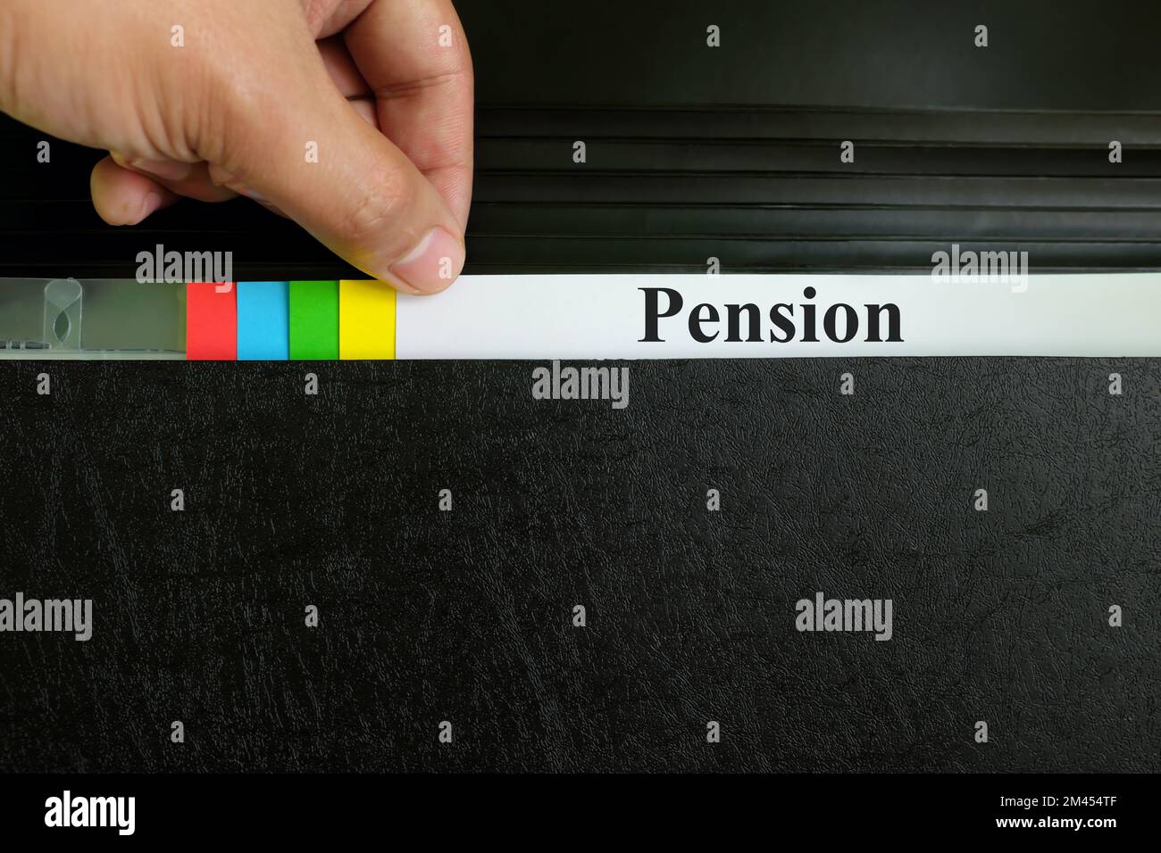 Hand picking pension file record in black binder folder. Pension benefit retirement concept. Stock Photo