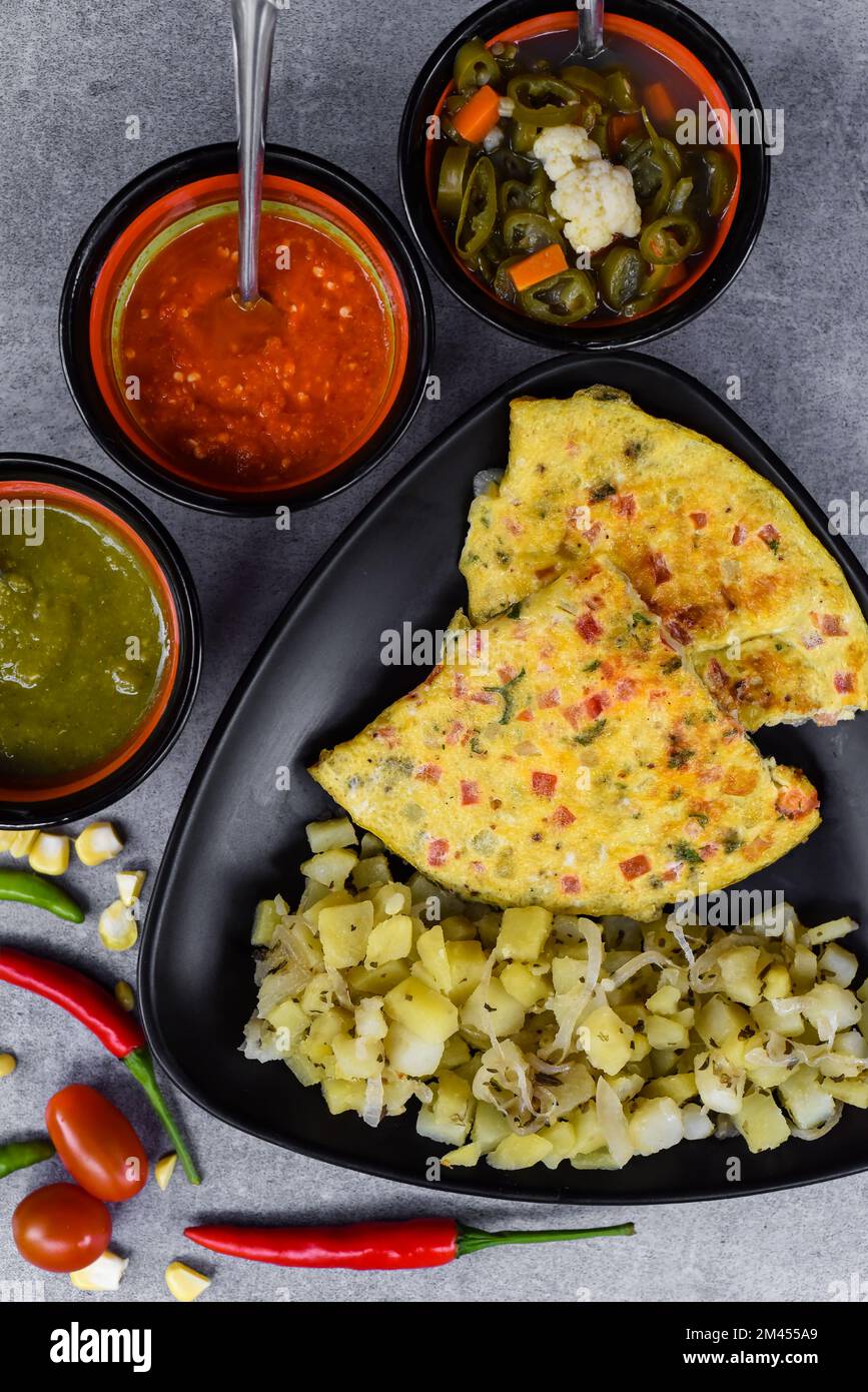 Mexican omelet with potato on black plate with latin american food on gray background Stock Photo