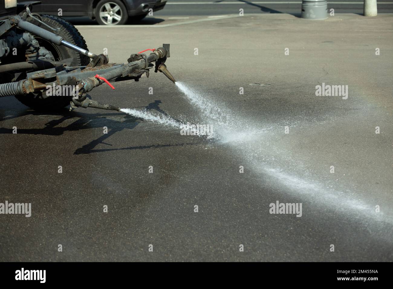 Car washes road. Tractor pours water. Washing off dirt from asphalt. Water jet from machine