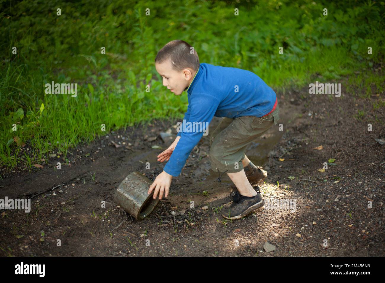 Child is holding dirty object. Little boy plays with concrete ring. Child found thing. Baby's adventure in summer. Stock Photo