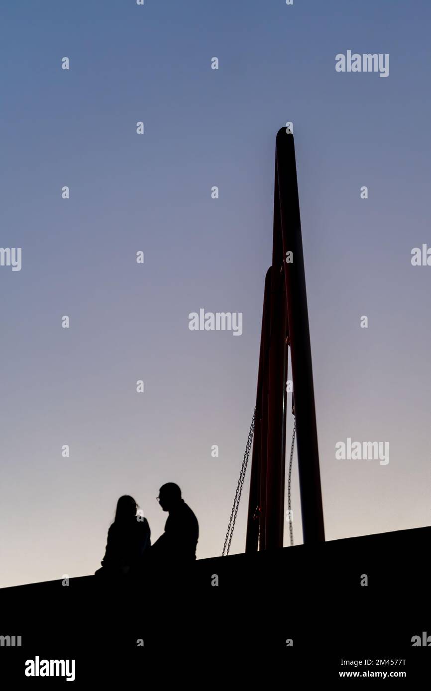 Dark silhouette of couple in love at picnic against the backdrop of a orange sunset Stock Photo