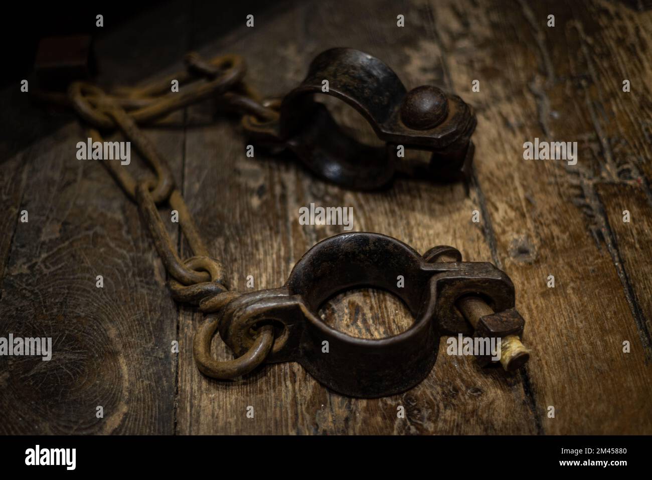 Ancient iron handcuffs on wooden floor from medieval times in England, prisoner wrist restraints. Stock Photo