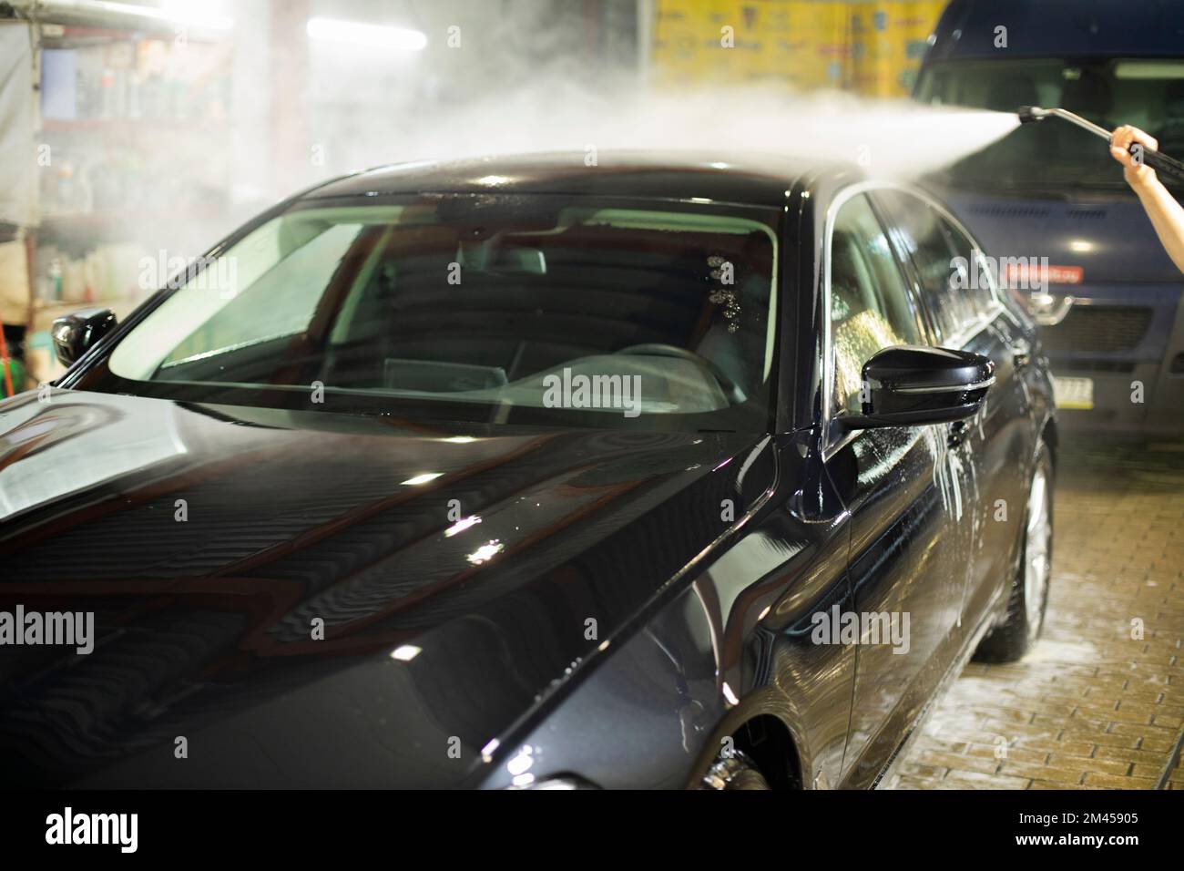 Car wash. Black car in car wash. Hot water jet. Washing off dirt from