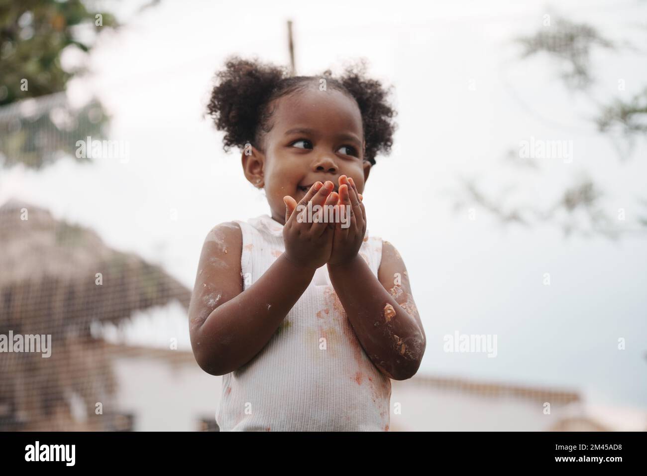 African-American child holding chicken egg with color stain on hand and dress. Stock Photo