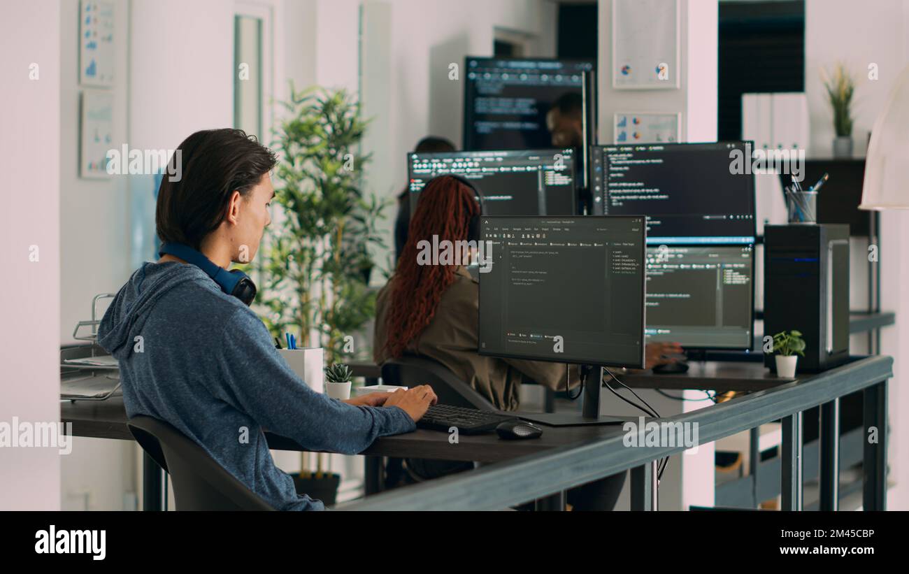 Asian software programer writing code on computer, displaying artificial intelligence algorithm. App developer coding database program, doing cloud computing with it server. Tripod shot. Stock Photo