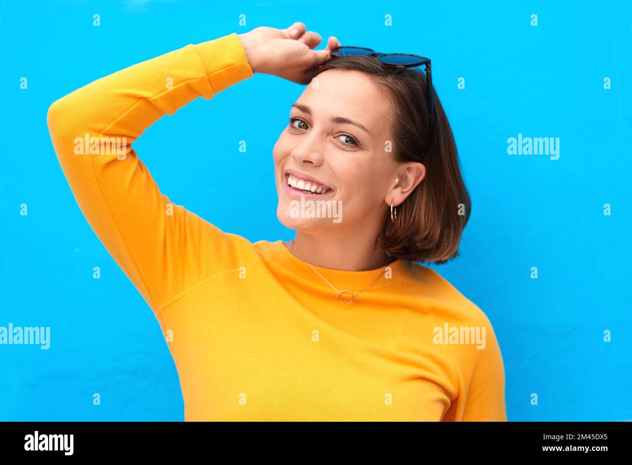 Nothing can dim her bright smile. Cropped portrait of a happy young woman posing against a blue background. Stock Photo