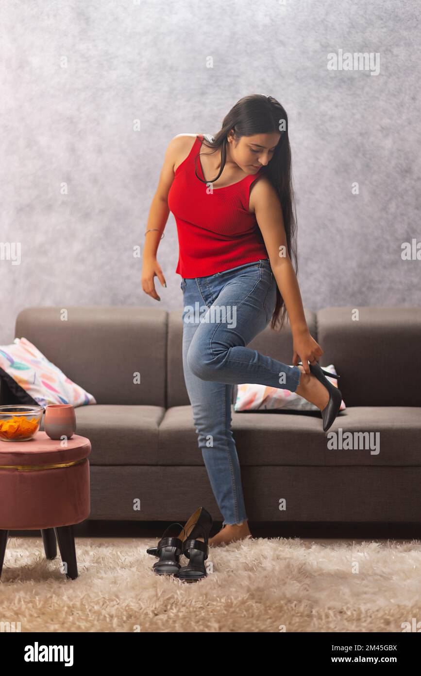 Teenager standing on one leg trying on high heels at home Stock Photo