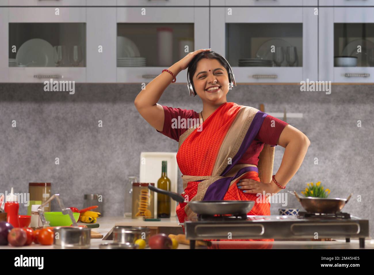 Woman with headphones dancing in the kitchen while cooking Stock Photo Alamy