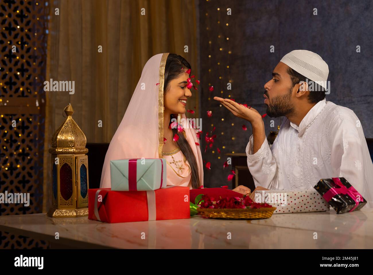 Muslim man blowing rose petals over his wife at home Stock Photo
