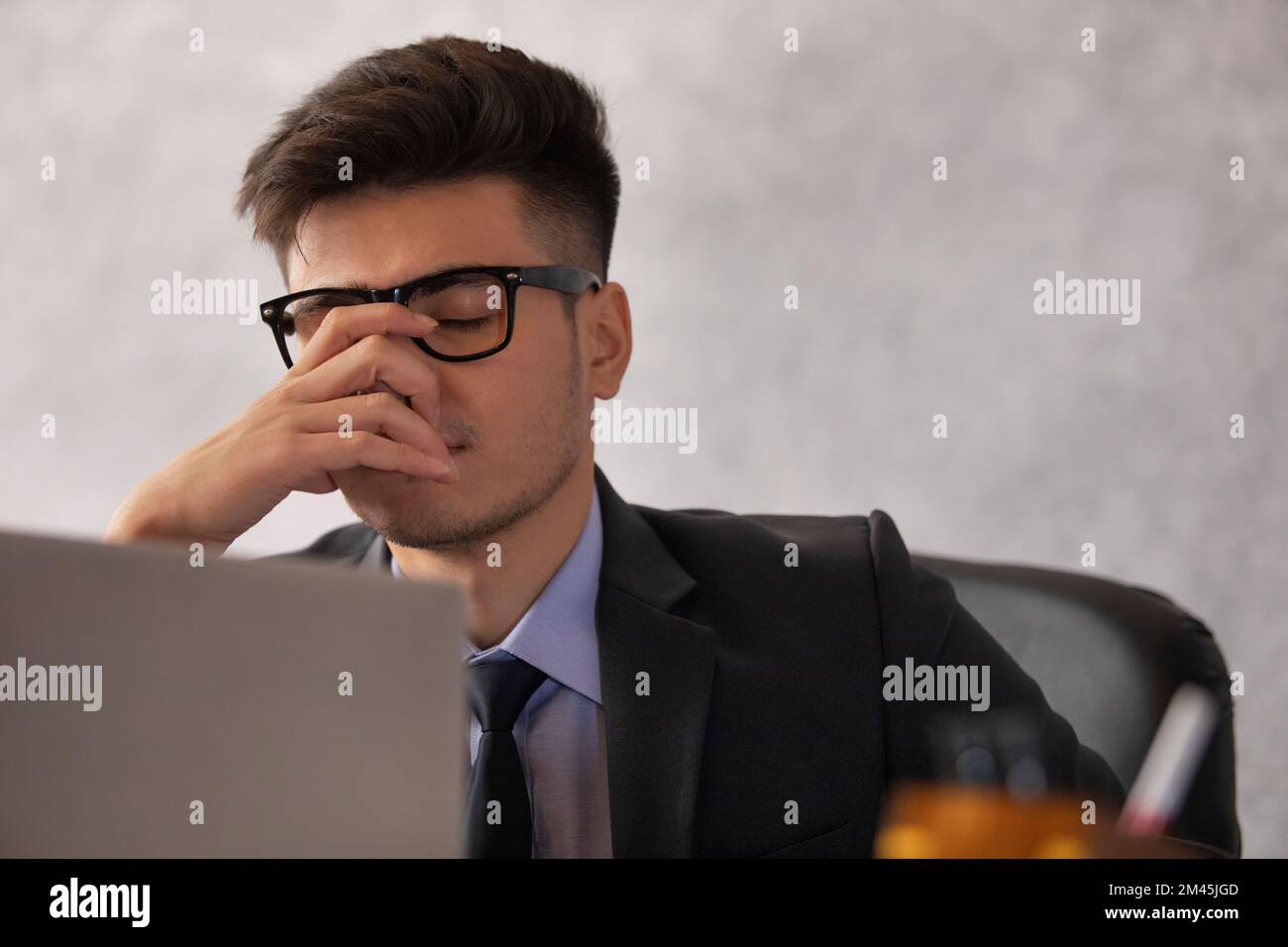 Close-up portrait of a stressed young businessman sitting at his desk in office Stock Photo