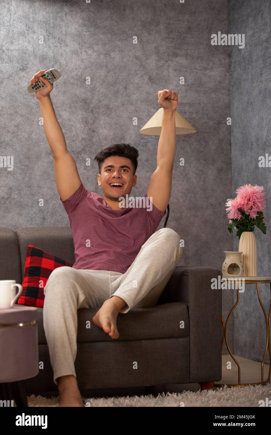 Young man cheering while watching a sports game on TV Stock Photo