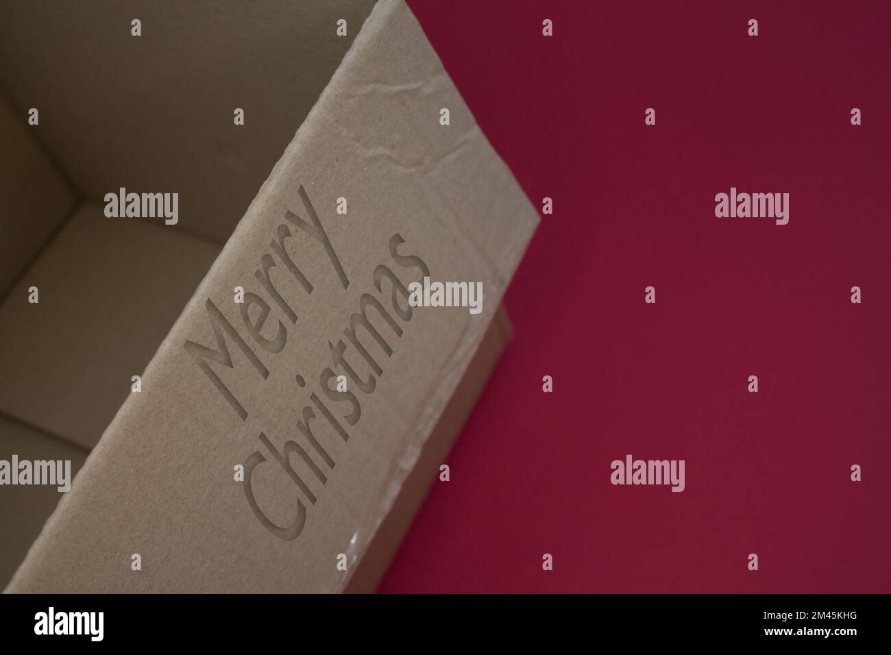 Merry Christmas word with cardboard box. Brown folded card box. Stock Photo