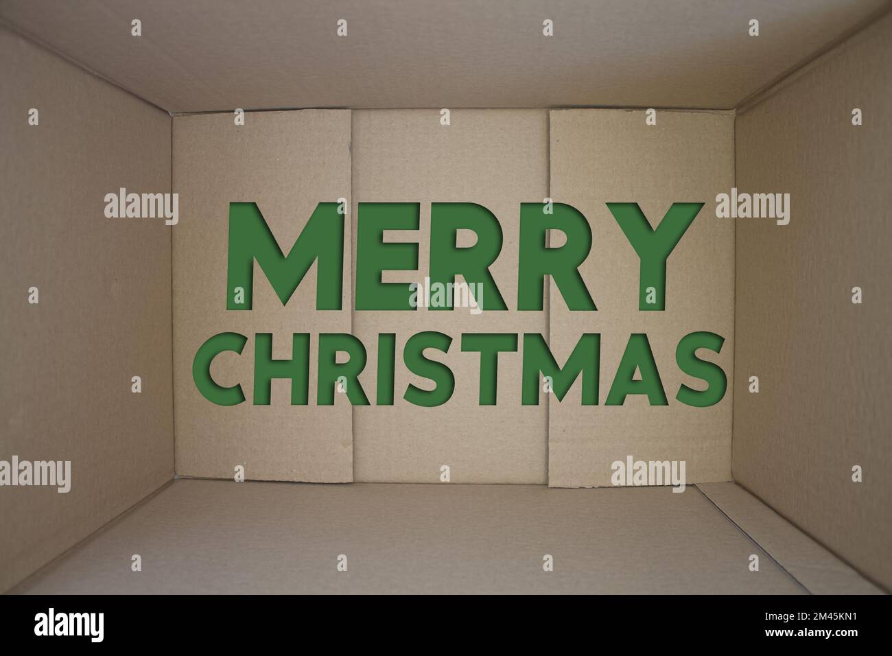 Merry Christmas word with cardboard box. Brown folded card box. Stock Photo