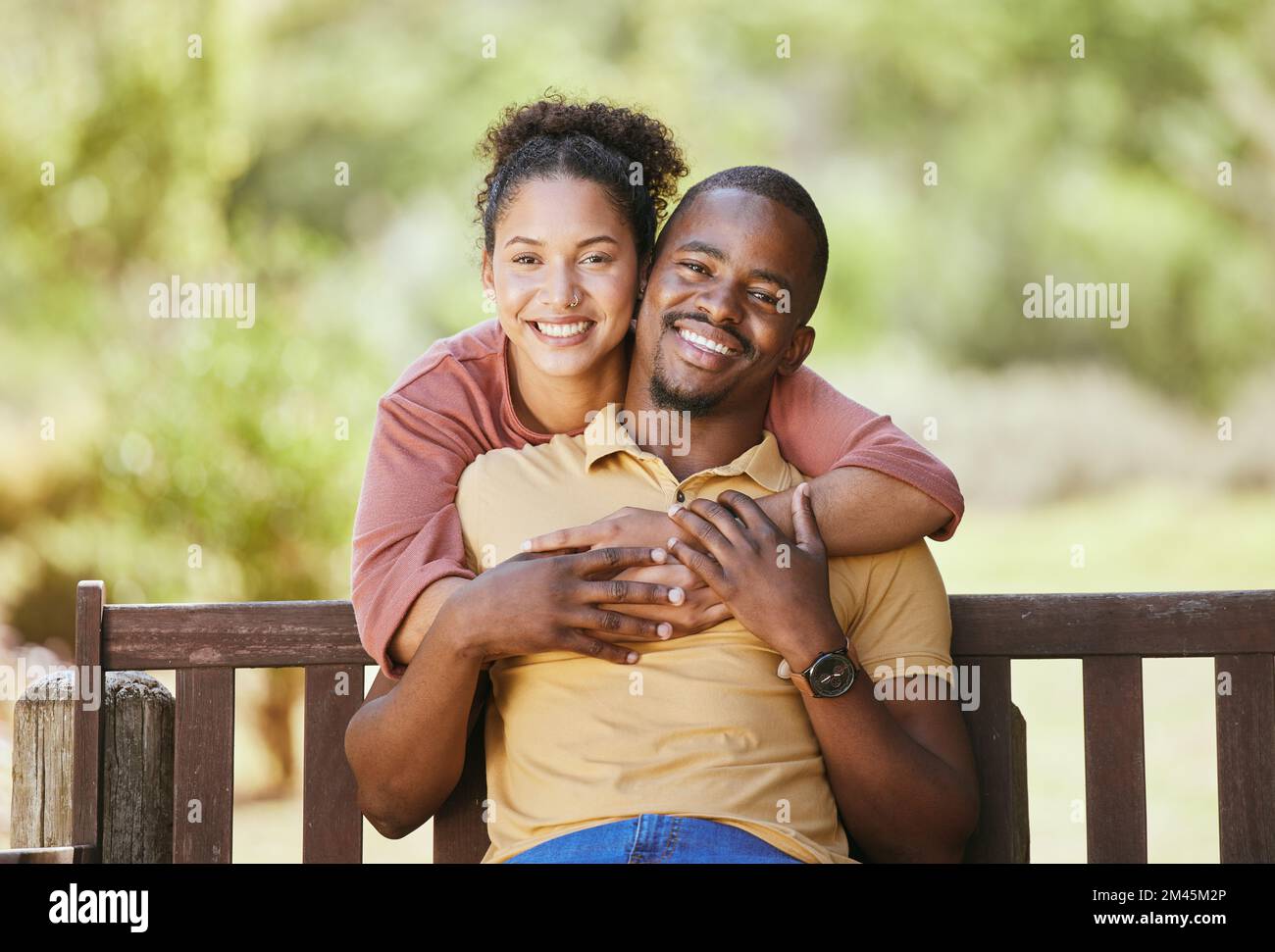 Love, portrait and couple hug in a garden, happy and smile while sitting, relax and bond in nature. Face, black family and man with woman in a park Stock Photo