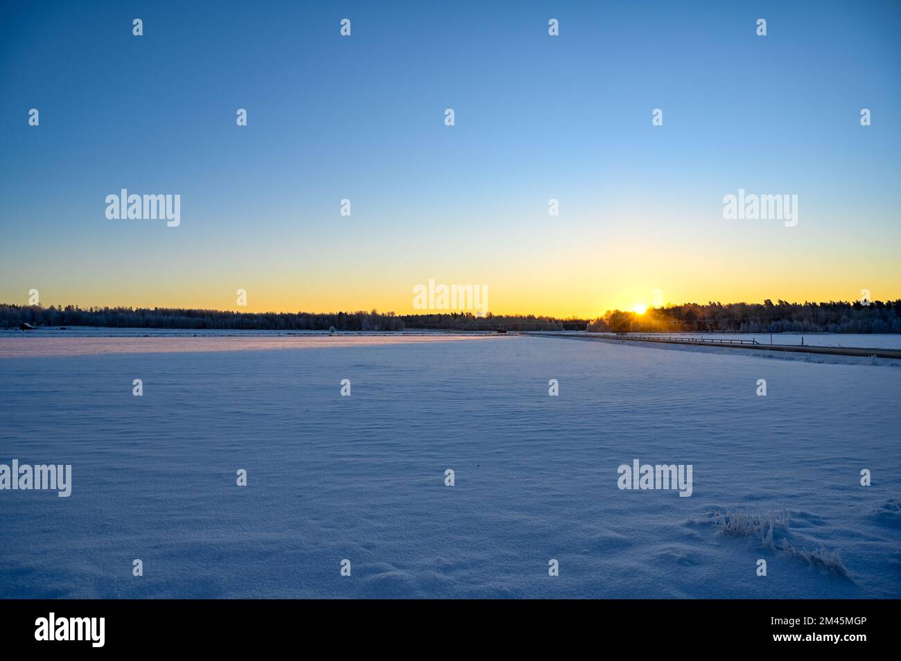 Sunrise a cold morning over field covered in snow Stock Photo