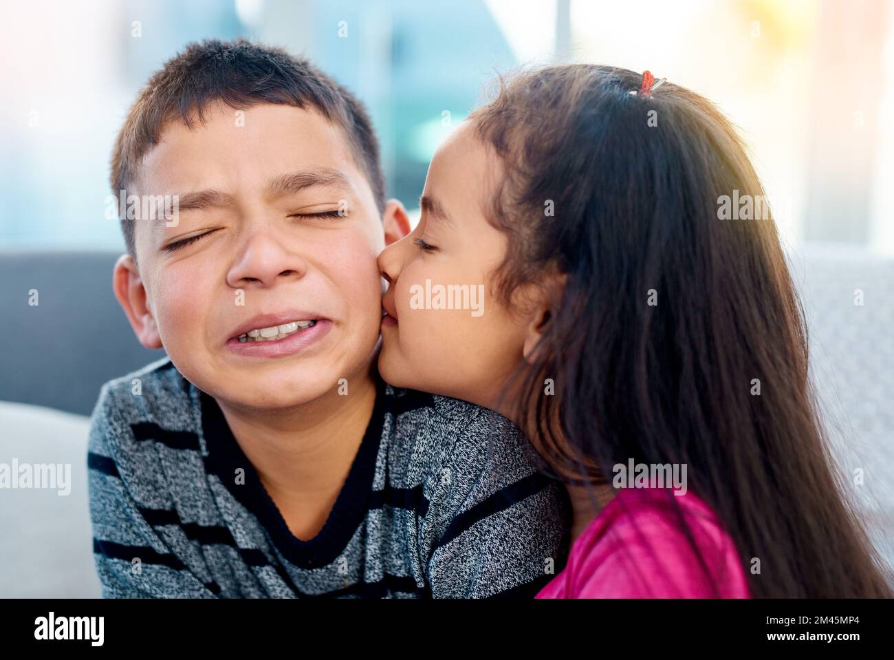First kiss nerves. an adorable little girl kissing her big brother on the cheek at home. Stock Photo