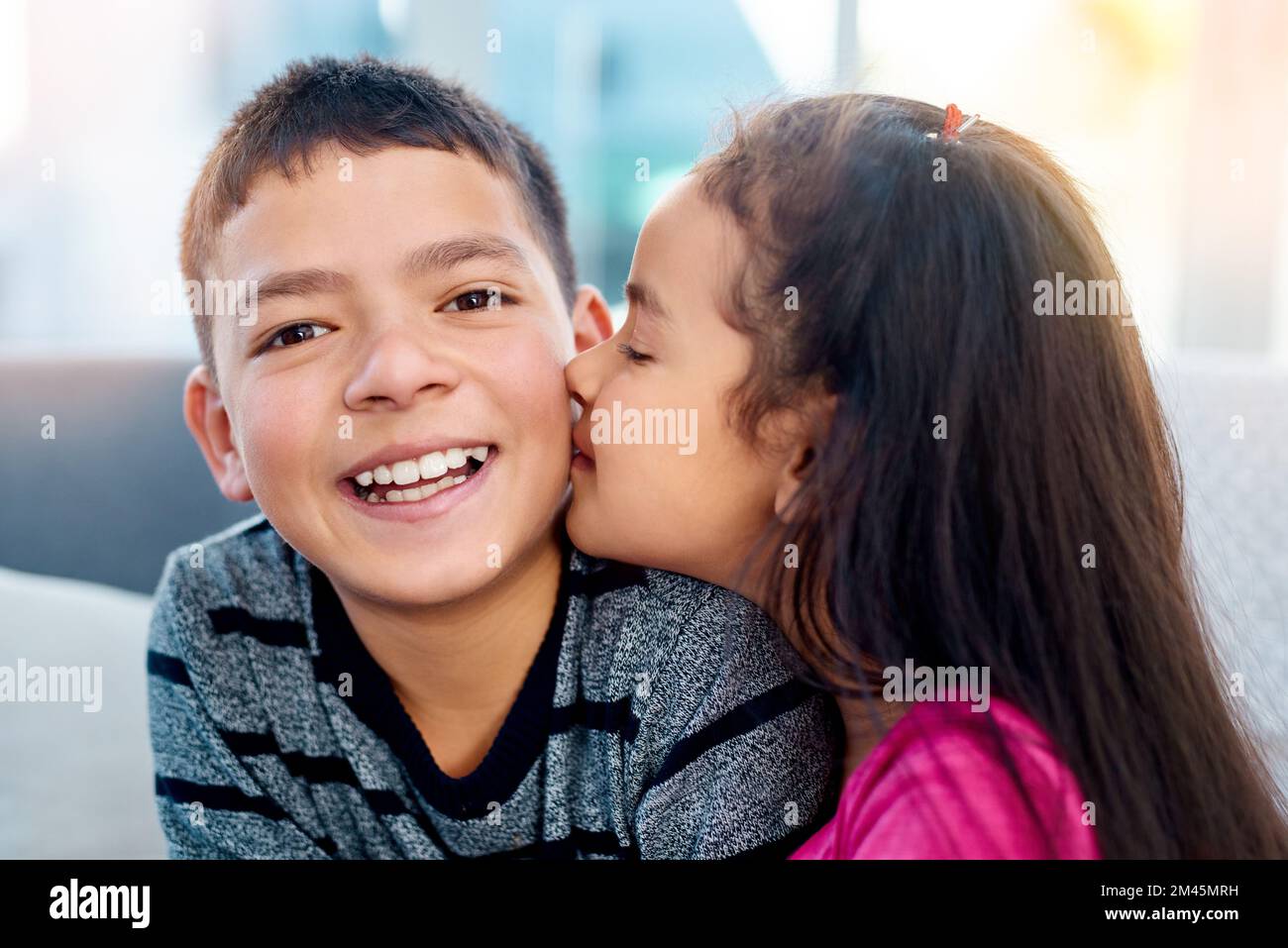 Okay that didnt feel so bad. an adorable little girl kissing her big brother on the cheek at home. Stock Photo