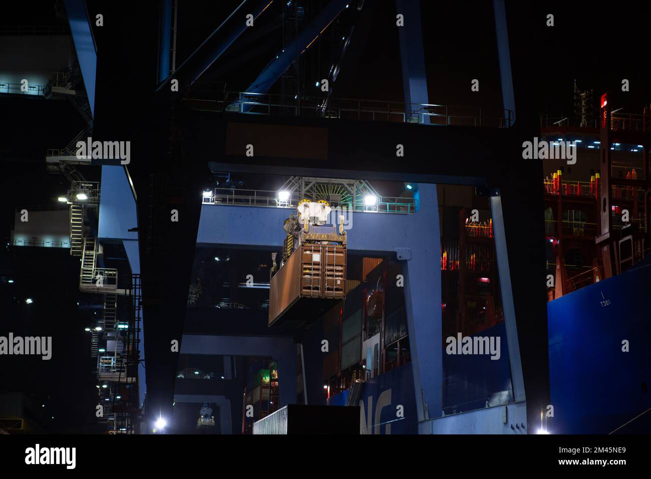 stacks of containers. operation of container terminal at night. Unloading container ship at night. Mooring cranes unload container ship at night Stock Photo