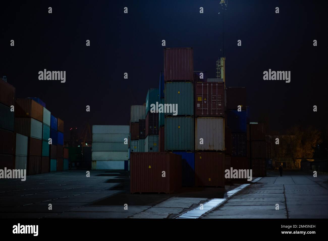 stacks of containers. operation of container terminal at night. Unloading container ship at night. Mooring cranes unload container ship at night Stock Photo