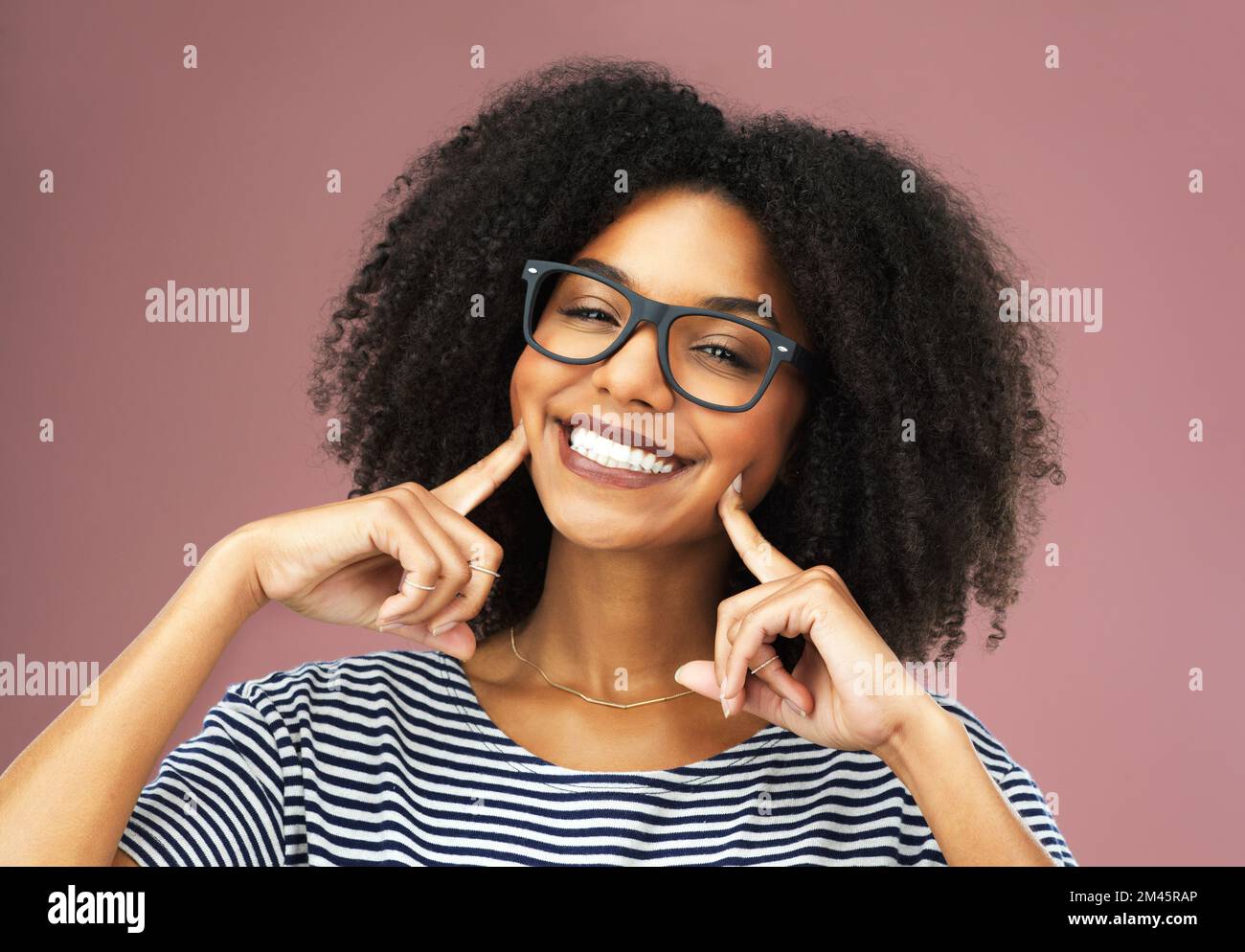 Just look at that smile. a beautiful young woman posing with her fingers on her cheeks. Stock Photo