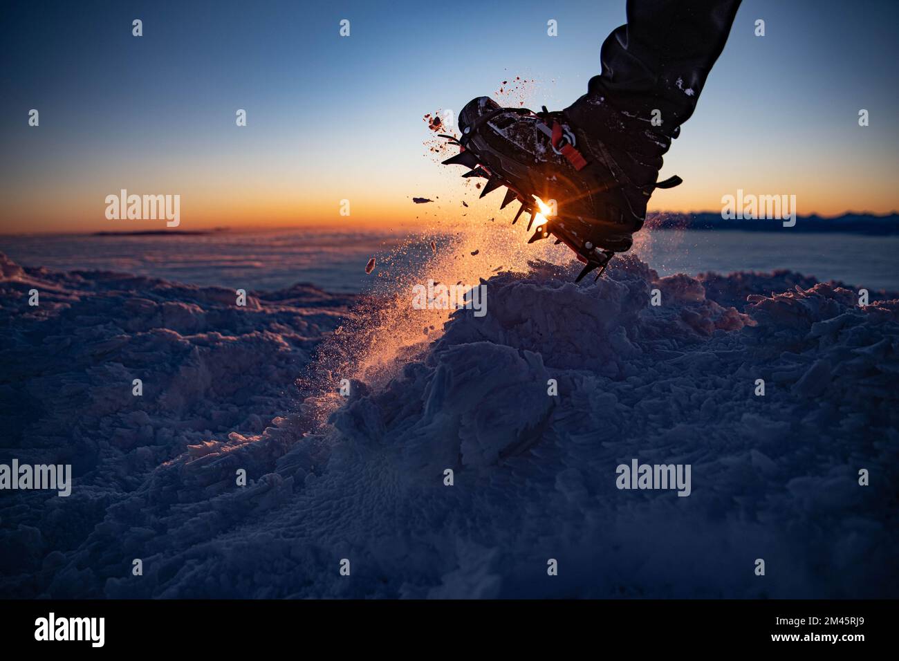 Man in crampon spike boots climbs to the top of a snowy mountain in winter.  Stock Photo