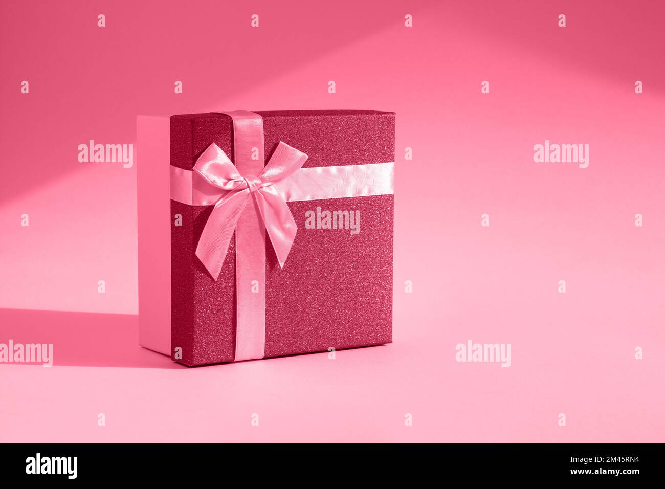 Viva magenta gift. The fashionable trending color of 2023. Tinted image of a gift box on a paper background. The concept of a holiday, birthday, Valen Stock Photo