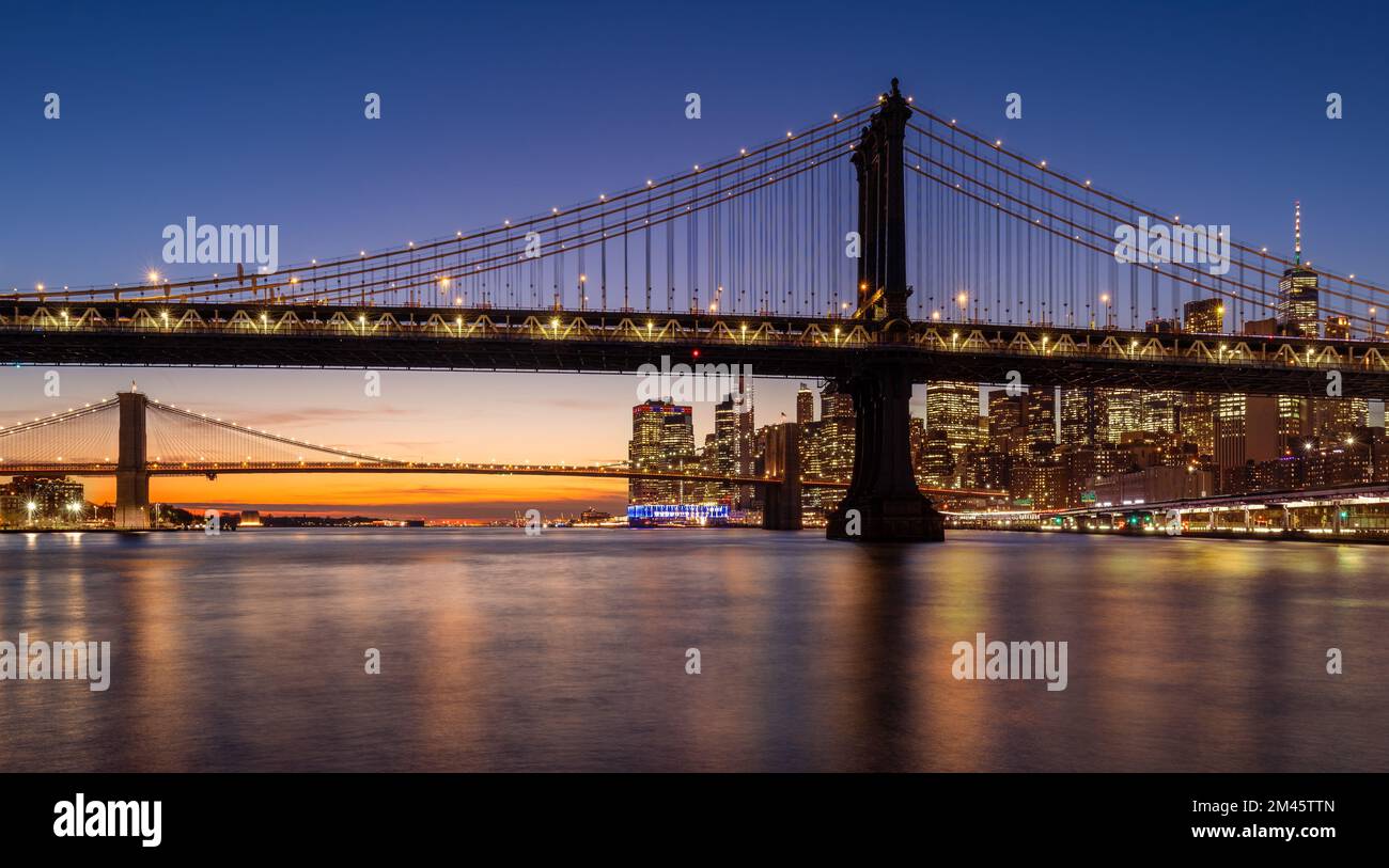 Manhattan Bridge and Brooklyn Bridge with East River just after sunset. Lower Manhattan skyline at dusk, New York City Stock Photo