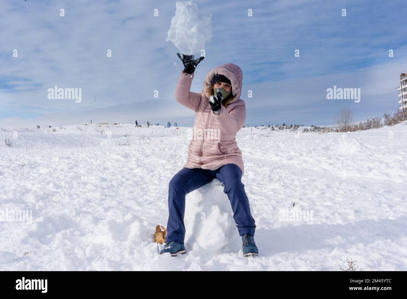 Woman playing with the snow while enjoying outdoors in a wintry day. Winter concept. Stock Photo