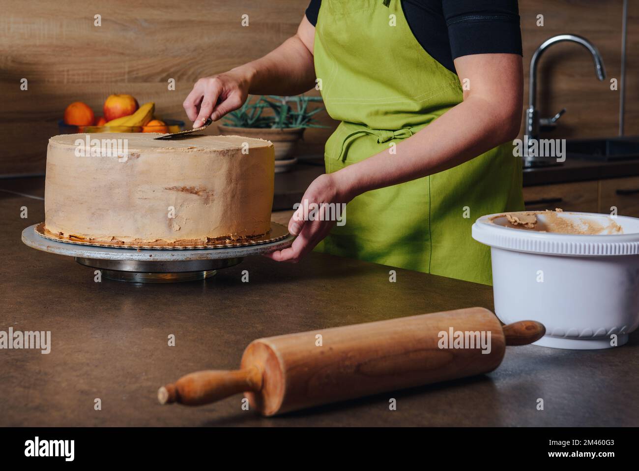 Unrecognisable woman decorating a delicious layered sponge cake with chocolate icing cream. DIY, sequence, step by step, part of series. Stock Photo