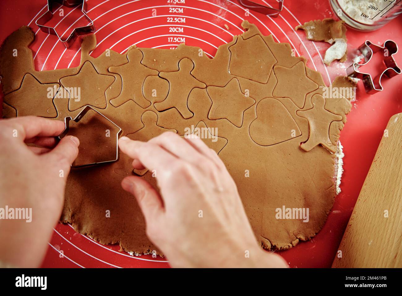 Woman preparing gingerbread cookies at kitchen. Female hands cutting ginger dough with cutter to making cookies for winter holidays Stock Photo