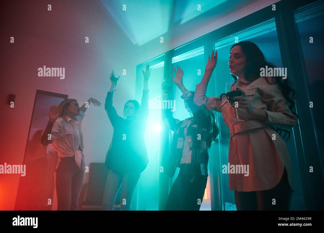 Young women having party inside contemporary barn house at night Stock