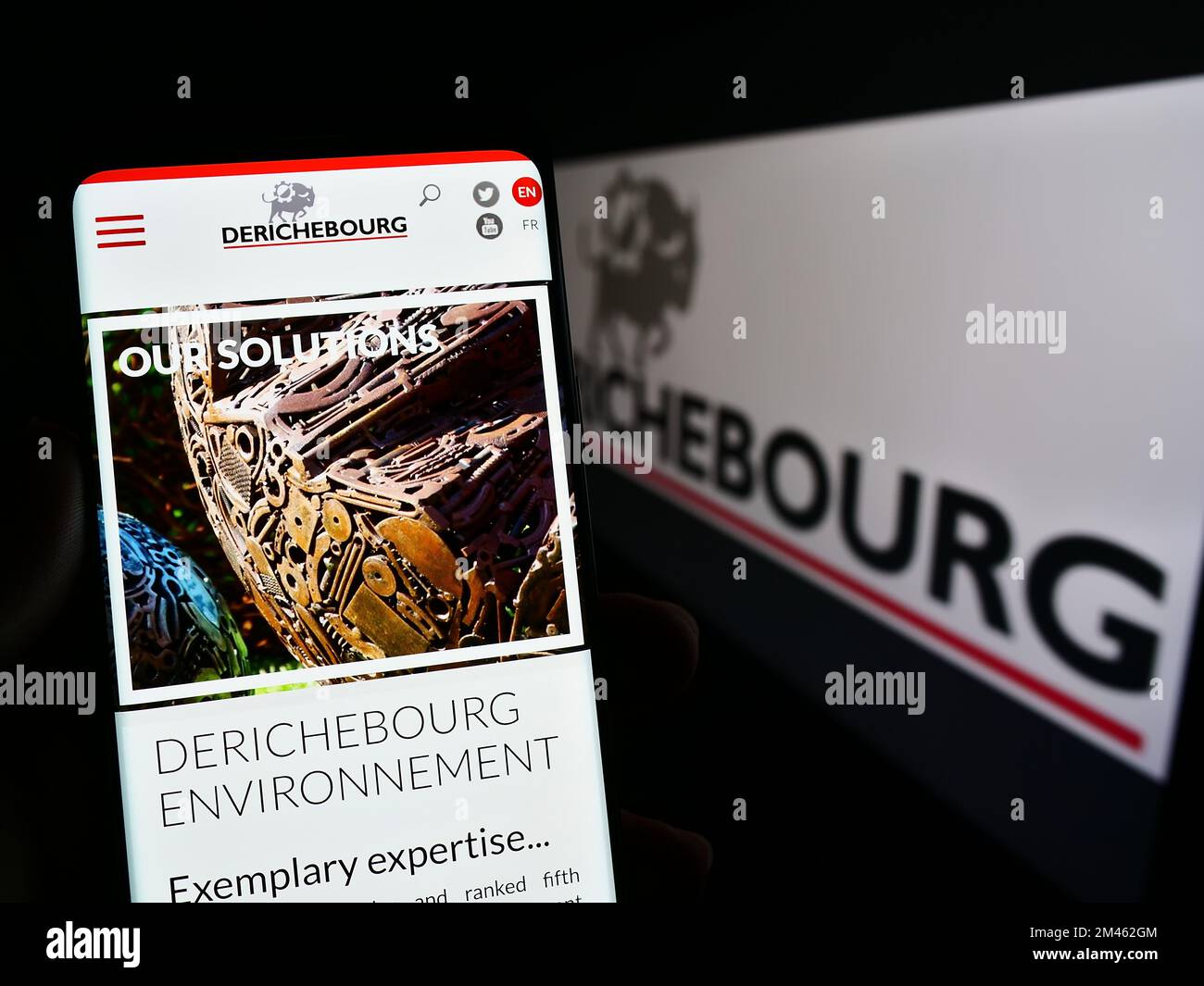 Smartphone with webpage of French recycling company Derichebourg S.A. on screen in front of business logo. Focus on center of phone display. Stock Photo