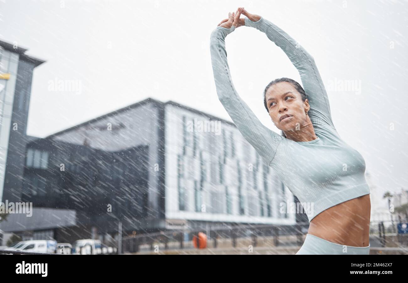 Black woman, stretching and fitness in rain and city for running training for a marathon. Workout, exercise and run goal motivation of a woman athlete Stock Photo