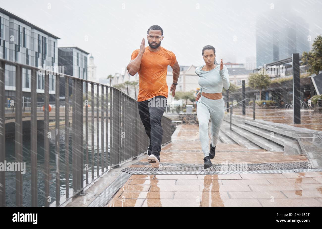 Fitness, city and couple in the rain running for workout, marathon training and exercise in winter. Sports, wellness and man and woman run for Stock Photo