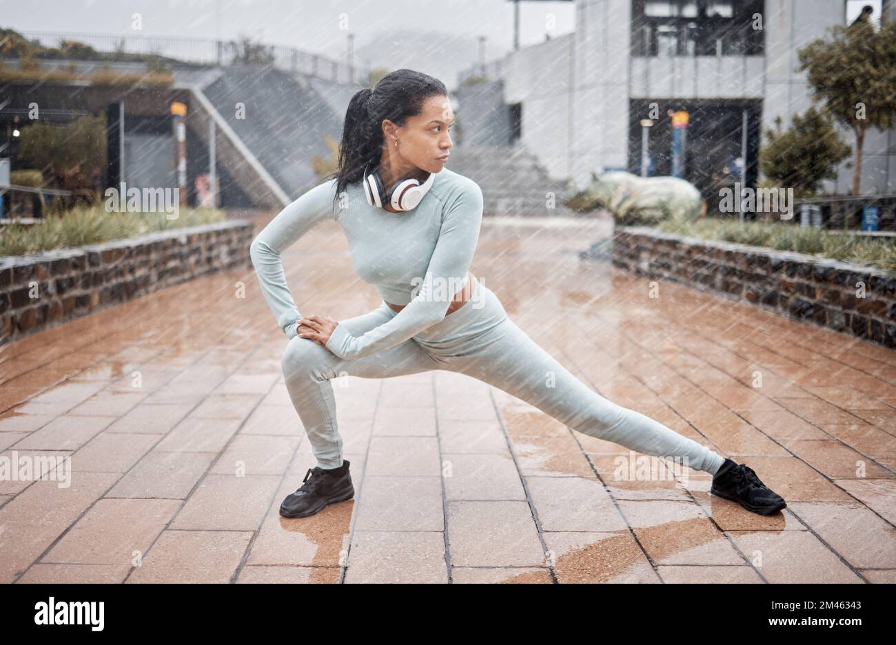 Rain, outdoor fitness and runner stretching for winter exercise, health training or start workout. Warm up, water drop and black woman focus with Stock Photo