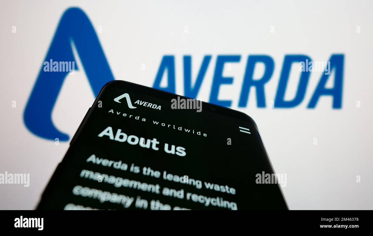 Mobile phone with webpage of Emirati company Averda International on screen in front of business logo. Focus on top-left of phone display. Stock Photo