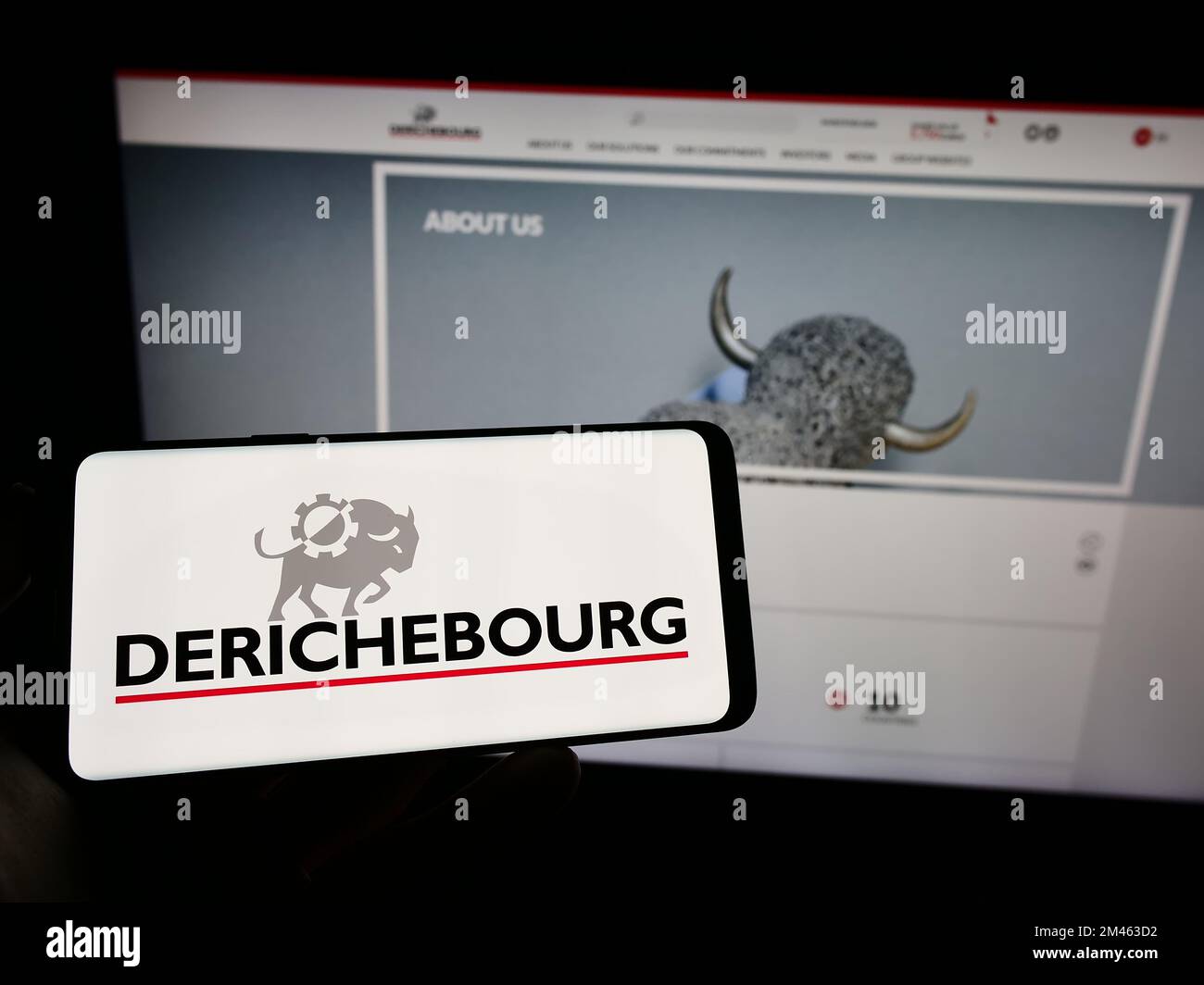 Person holding mobile phone with logo of French recycling company Derichebourg SA on screen in front of business web page. Focus on phone display. Stock Photo