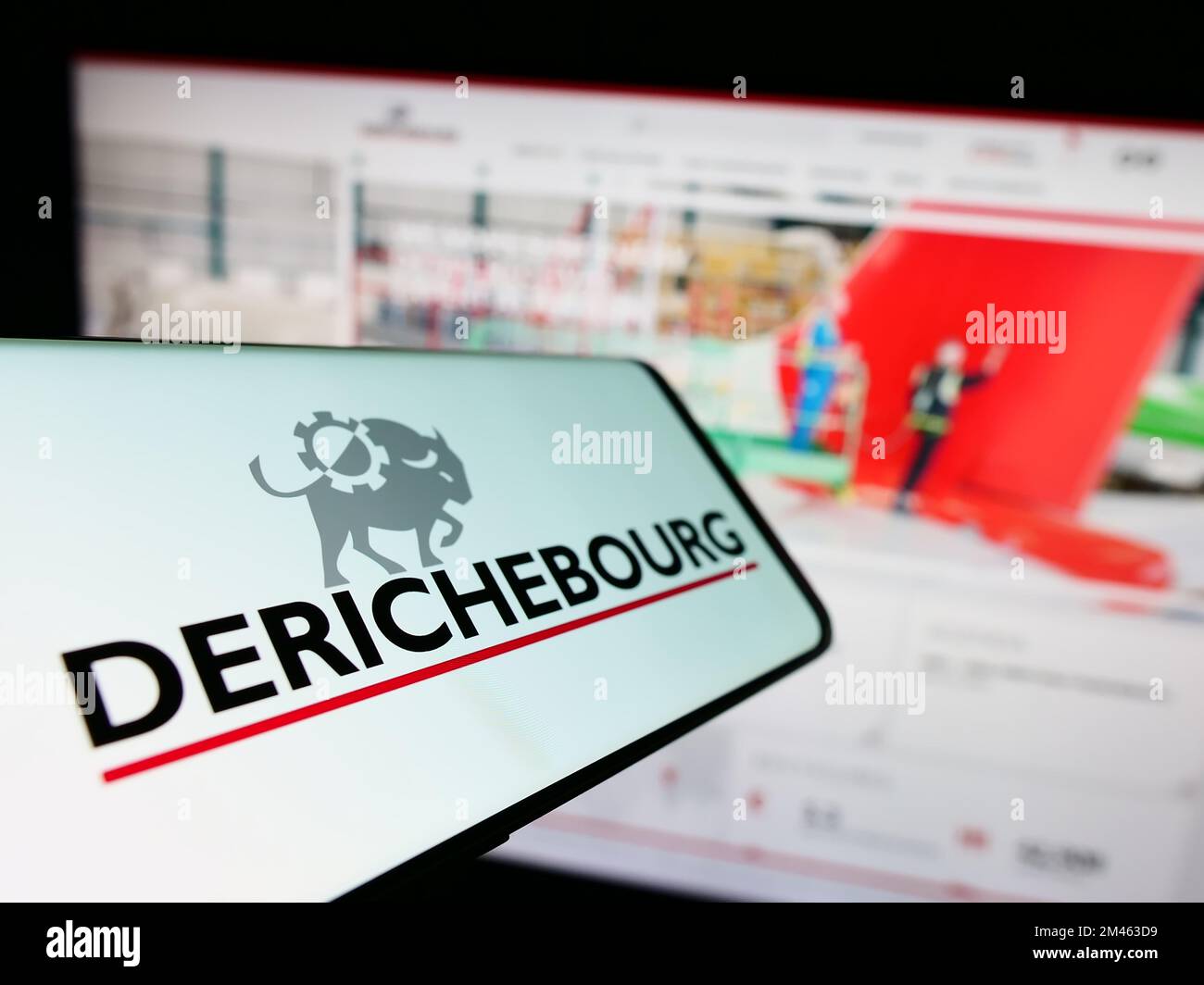 Mobile phone with logo of French recycling company Derichebourg S.A. on screen in front of website. Focus on center-left of phone display. Stock Photo