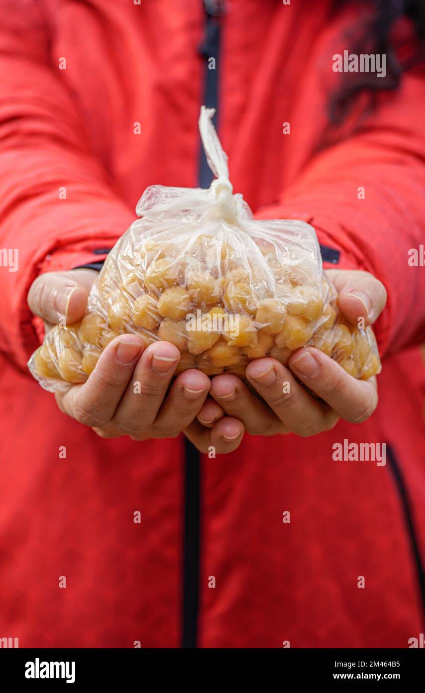 hold a bag of nutritious chickpeas in hand with red background Stock Photo