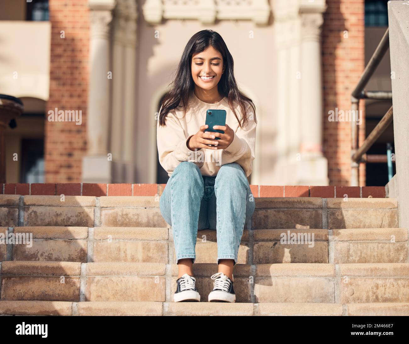 Student, smile or girl with phone on stairs for communication, 5g network or social media news app reading outdoor. Happy, mobile or woman with Stock Photo