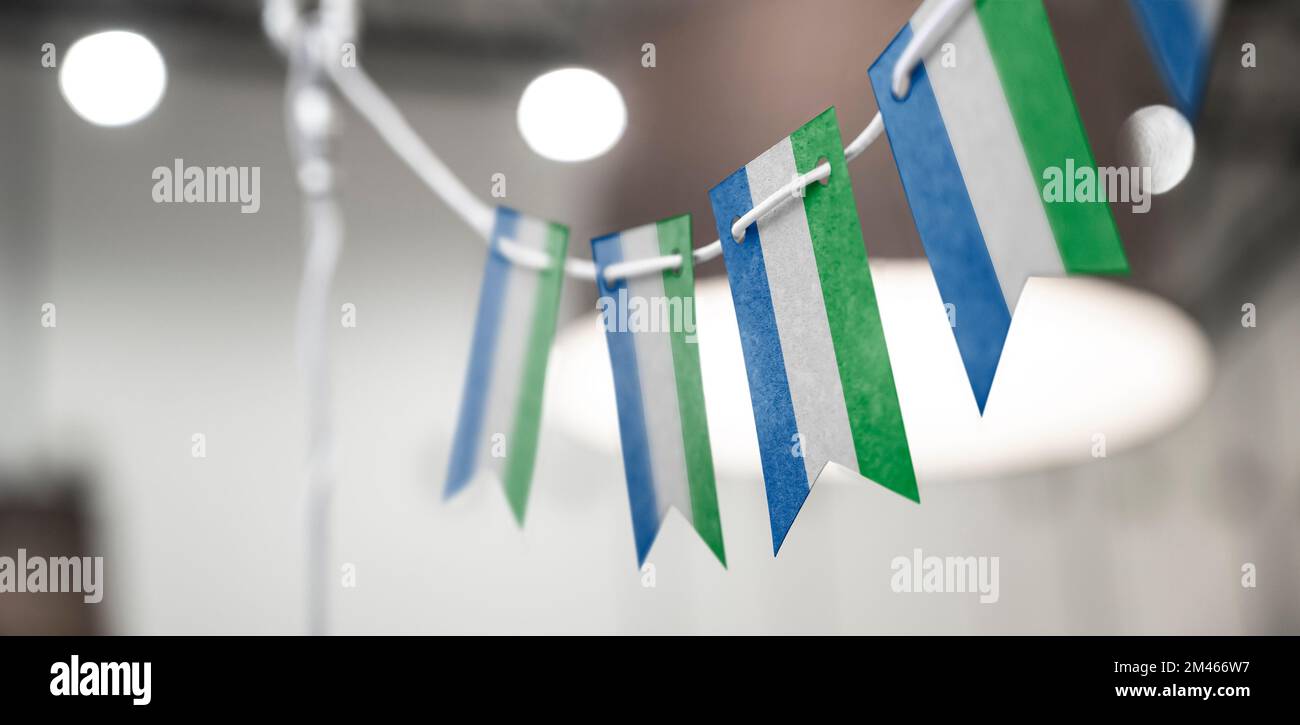 A garland of Sierra Leone national flags on an abstract blurred ...